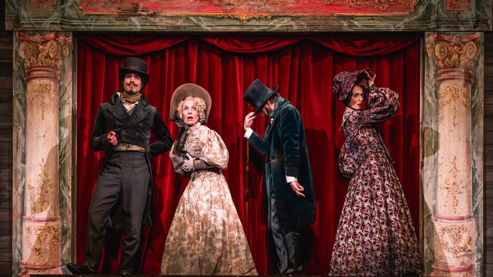 Vier Schauspieler in historischen Kostümen auf einer Theaterbühne.