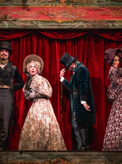 Vier Schauspieler in historischen Kostümen auf einer Theaterbühne.