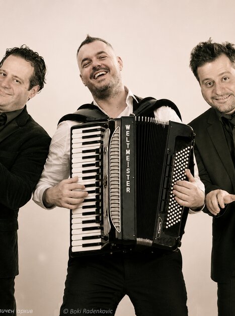 Three musicians pose together with trumpet and accordion. | © личен архив - Boki Radenkovic - IA gen