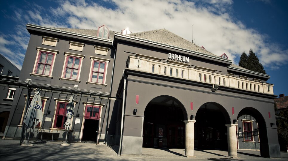 Außenansicht des Orpheum Graz bei Tag mit markanter grauer Fassade und Rundbögen. | © Spielstätten - Lupi Spuma