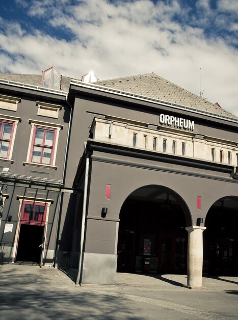 Außenansicht des Orpheum Graz bei Tag mit markanter grauer Fassade und Rundbögen. | © Spielstätten - Lupi Spuma
