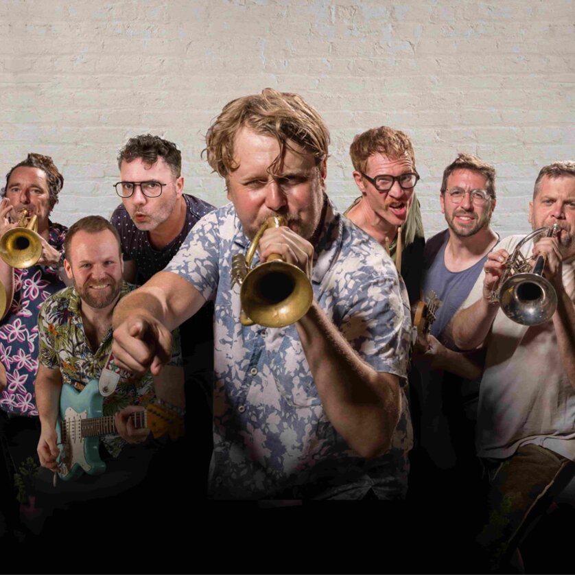 A group of musicians with trumpets and a guitar pose energetically for the photo. | © David Königsmann