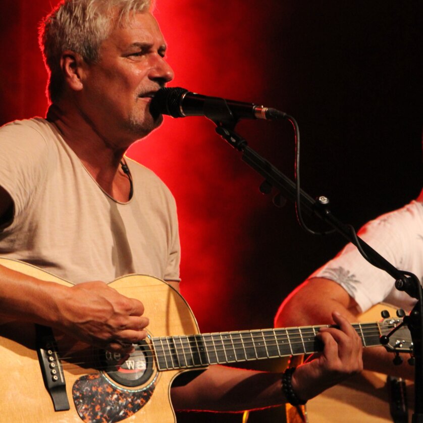 Zwei Männer spielen Akustikgitarren und singen auf einer Bühne. | © Josef Hofmüller