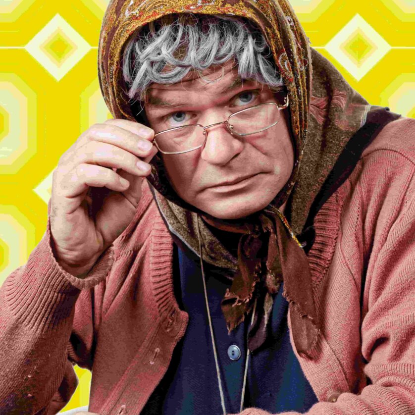 Ein verkleideter Mann der als ältere Dame im Rollstuhl mit grauen Haaren und Brille mit einem skeptischen Blick. | © Markus Wache