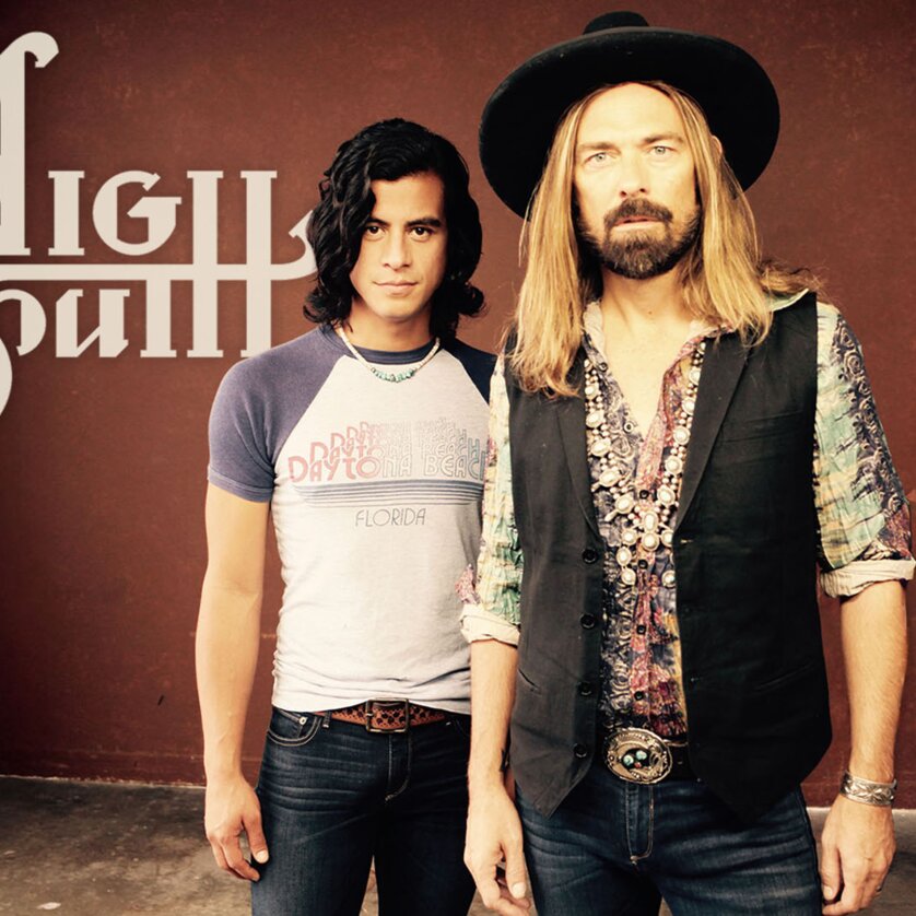 Zwei Musiker von High South posieren vor einem roten Hintergrund mit Logo. | © Jim Shea