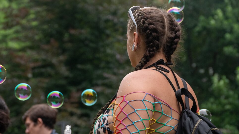 Junge Frau mit Zöpfen und Netzoberteil, umgeben von Seifenblasen. | © Maya Hanl