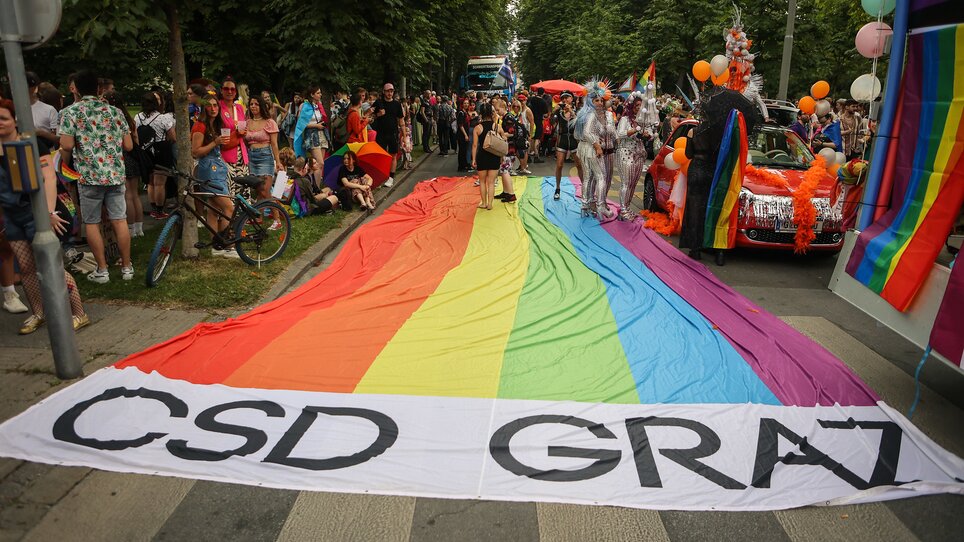 Bunte Parade mit Regenbogenflagge und Menschen in Graz. | © Sebastian Neugebauer