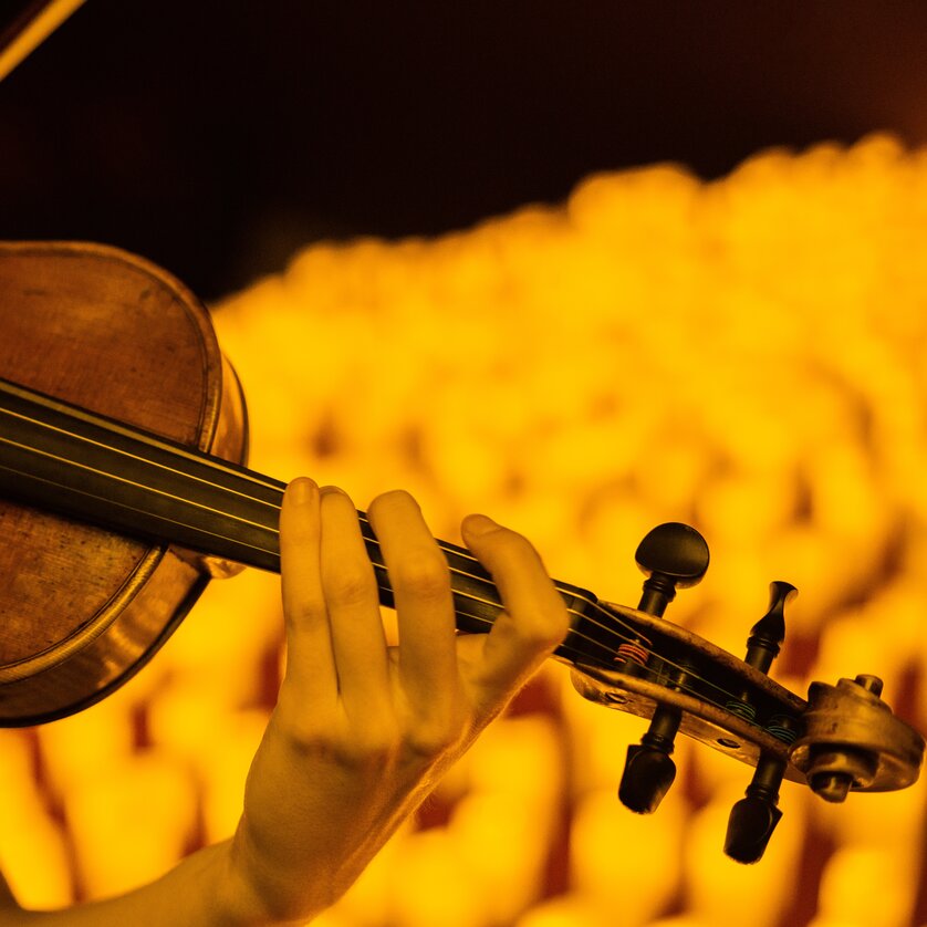 Candlelight concert violin | © Fever Close-up of a violin played by hand in warm candlelight | © Fever