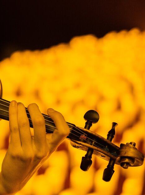 Close-up of a violin played by hand in warm candlelight | © Fever