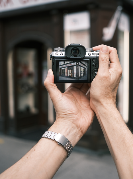 Una persona scatta una foto a un'insegna di un negozio con una macchina fotografica. | © Maria Alberer