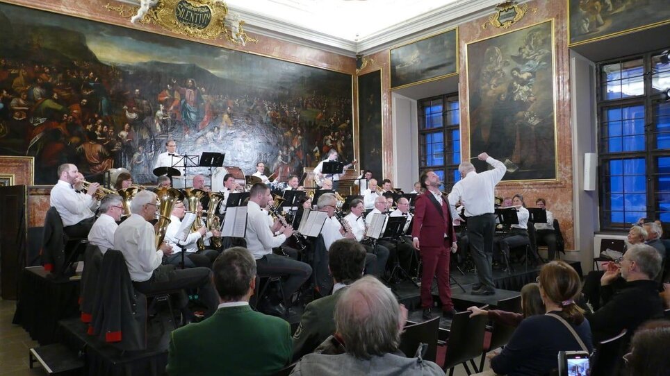 An orchestra performs in a grand hall adorned with historic paintings. | © lizenzfrei