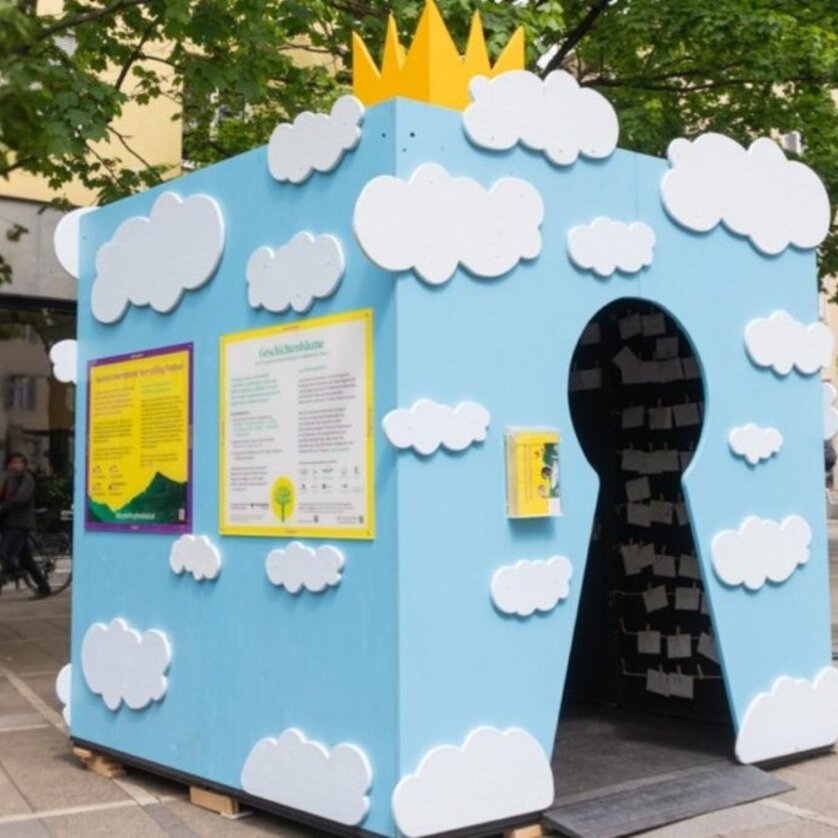 Eine hellblaue Hütte mit weißen Wolkenmotiven und einer gelben Krone, die im Rahmen des Festivals "Graz erzählt" ein Märchenschloss darstellen soll. | © Moritz Pirker