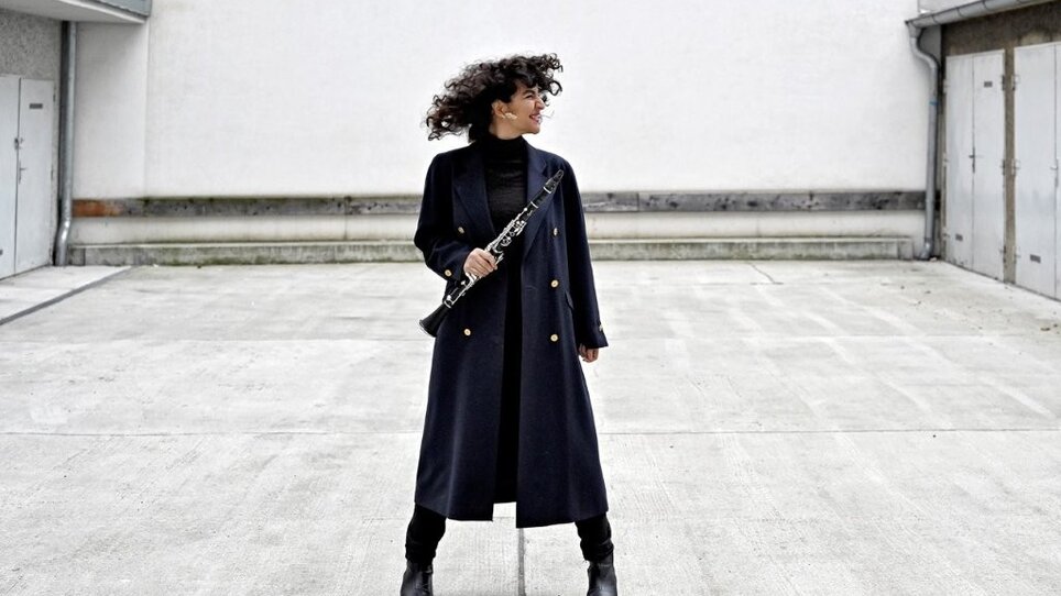 Mona Matbou Riahi tiene in mano un clarinetto in uno spazio urbano. | © Nina Streets