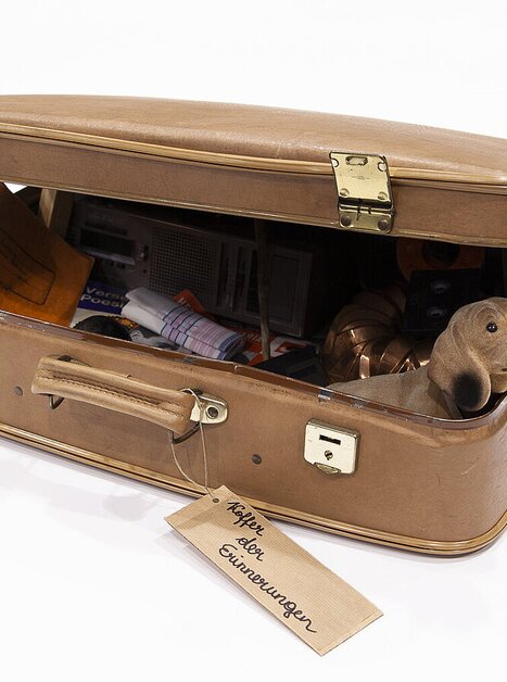 Ein geöffneter Koffer voller Gegenstände und einer Hundefigur. | © Magdalena Gföllner