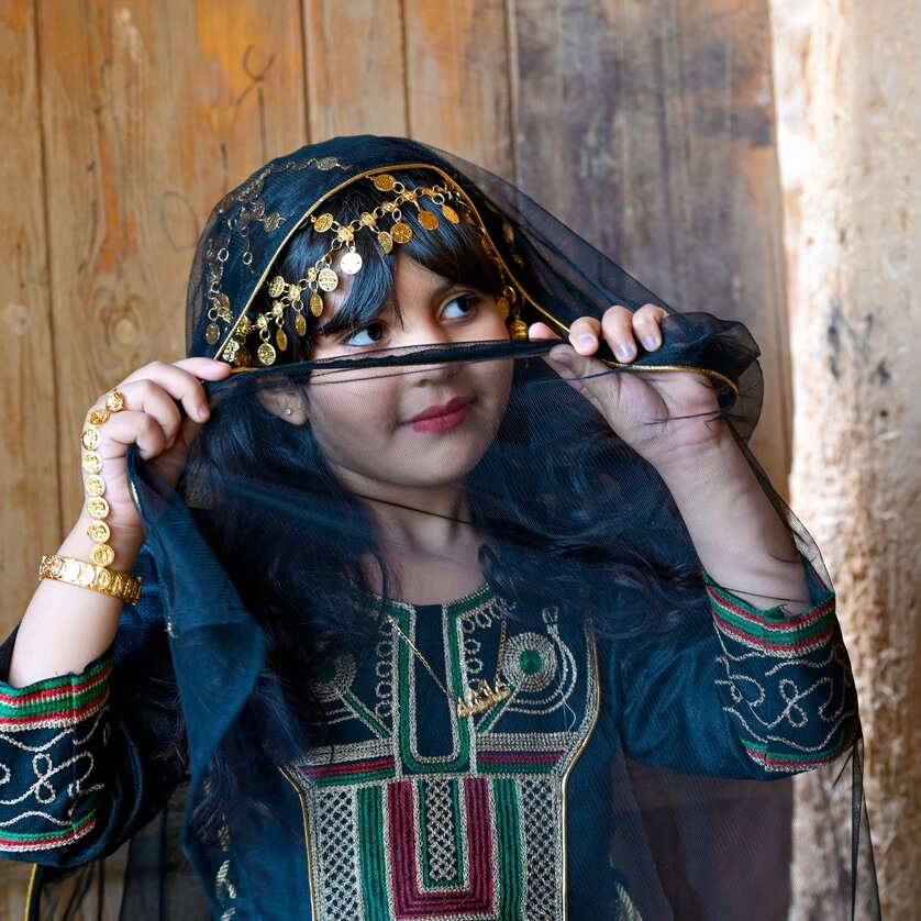 Ein Mädchen in traditioneller Kleidung mit einem Schleier und goldenen Accessoires. | © Gerhard Huber
