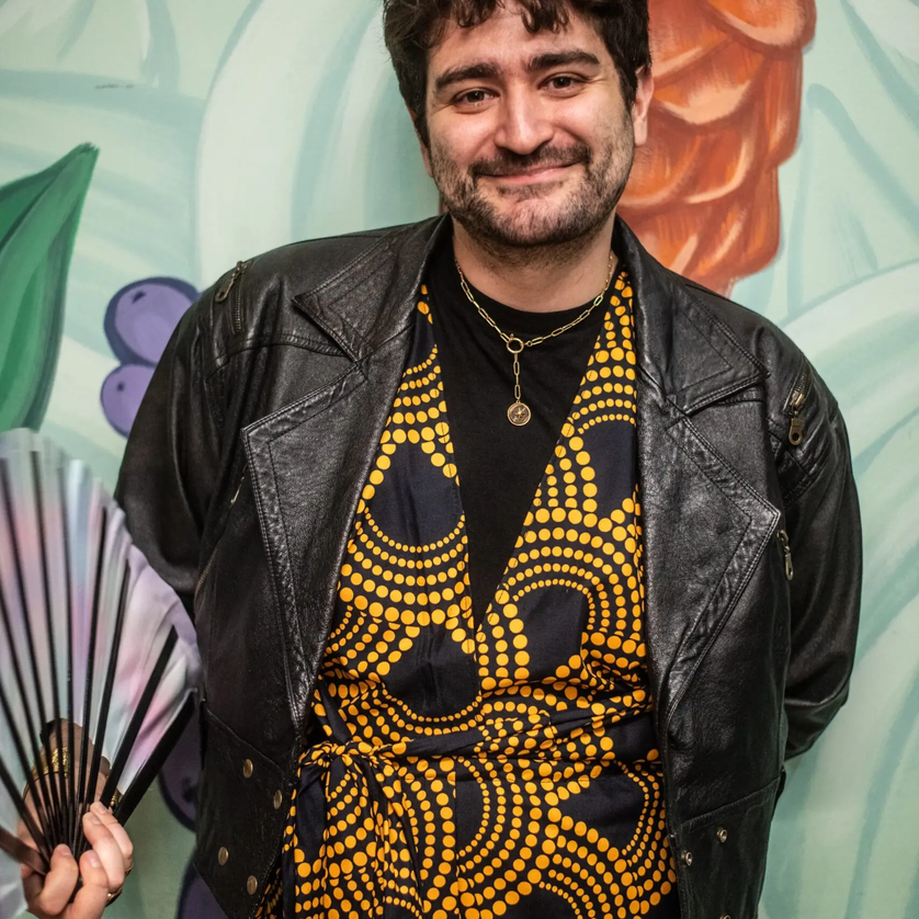Ein Mann in Lederjacke und gemusterter Kleidung mit Fächer. | © Julian Pöschl