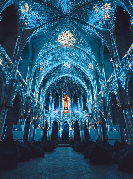 Beleuchtete, verzierte Kathedrale mit Sitzkissen im Vordergrund. | © Projektil