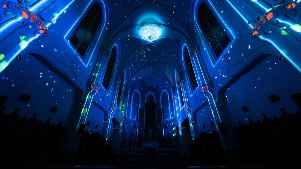 Futuristische Lichtinstallation in einer Kirche mit Sternen im Dunkeln. | © Projektil