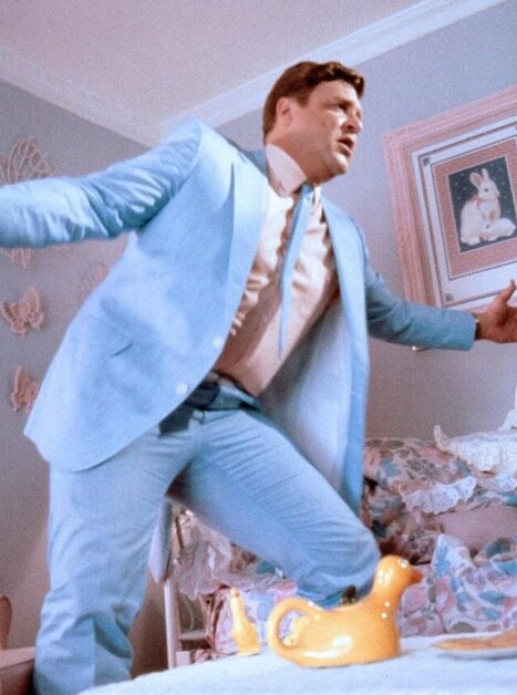 Mann im hellblauen Anzug performt in einem Zimmer mit pastellfarbenen Wänden. | © 1986 Warner Bros. - Jonathan Demme