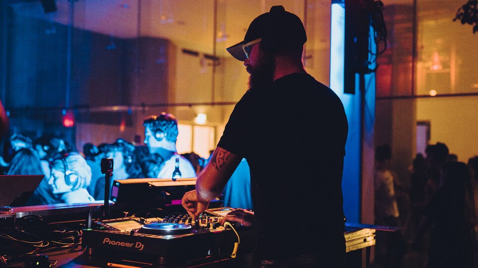 Un DJ suona musica a un evento con luci colorate. | © Silent Disco Austria