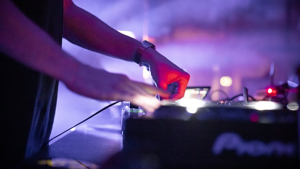 Un DJ si concentra sul suo equipaggiamento durante un'esibizione dal vivo. | © Silent Disco Austria