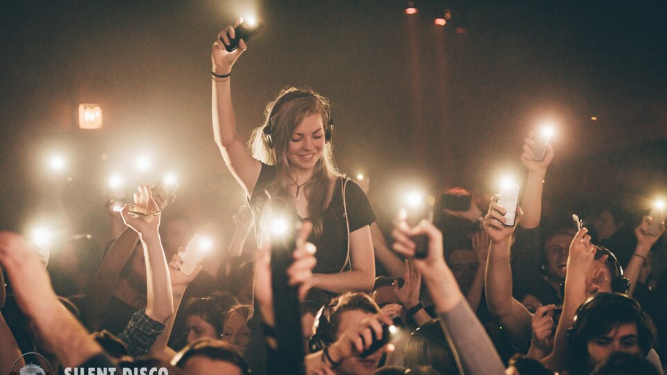 Il pubblico alza le mani con luci durante una silent disco. | © Silent Disco Austria