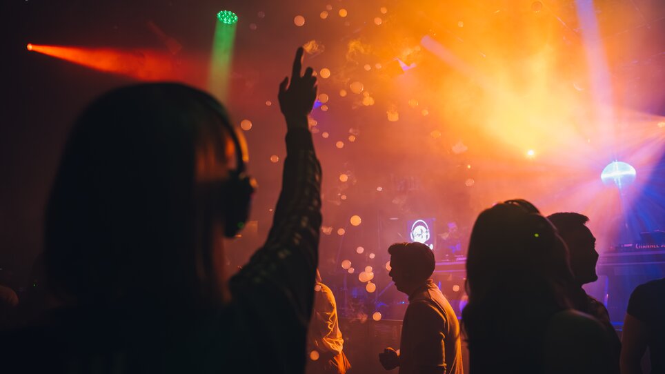 Persone che ballano circondate da luci colorate e nebbia. | © Silent Disco Austria