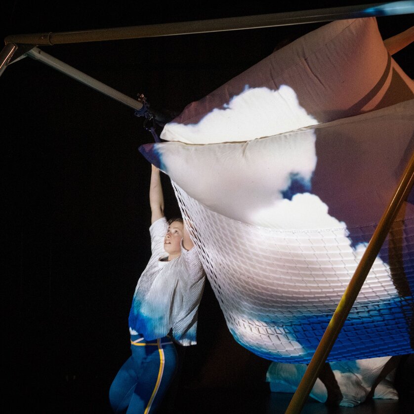 Eine Tänzerin interagiert mit einem großen, wolkenartigen Objekt auf der Bühne. | © Kurt van der Elst