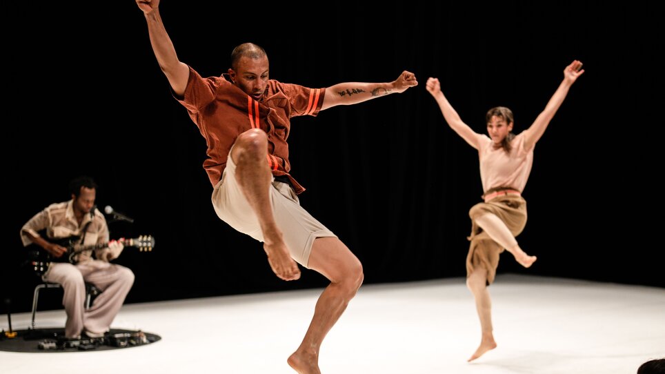 Zwei Tänzer in Bewegung, begleitet von einem Musiker mit Gitarre. | © Matthias Wäckerlin