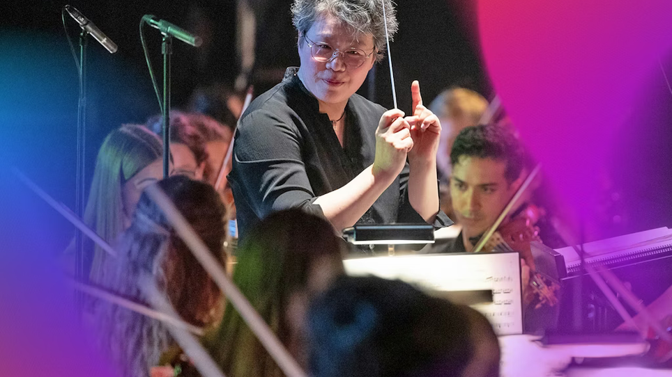 Conductor Mei-Ann Chen stands in front of an orchestra and conducts with passion. | © Milatovic
