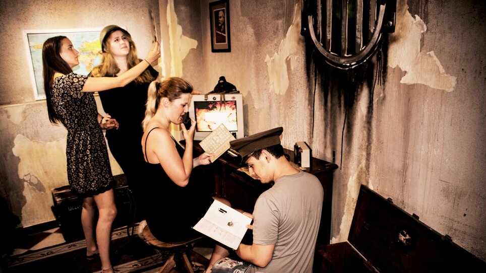 Vier Personen erkunden einen Escape Room mit spannenden Rätseln.