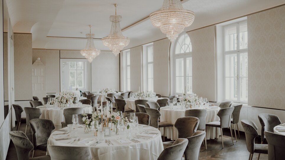 Elegant tables and chairs in a bright, modern venue. | © Aiola im Schloss