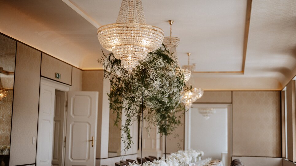 Stylish room with crystal chandeliers and floral arrangements for an event. | © Stefan Mang Photography