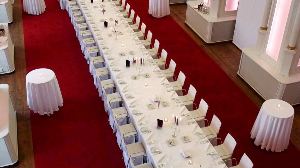 Long banquet setup with elegant table decor in a bright room. | © Alte Universität