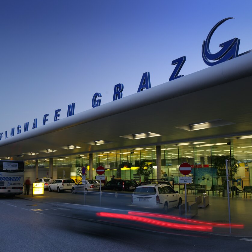 Der Flughafen Graz mit modernen Architekturelementen, beleuchtet bei Dämmerung. | © Graz Tourismus - Harry Schiffer