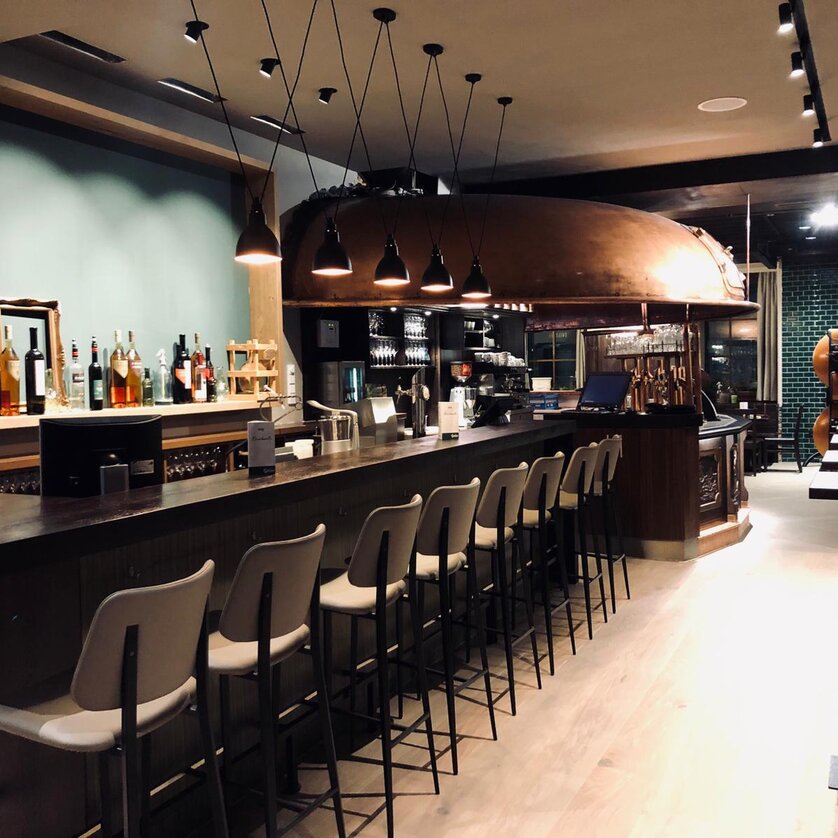 Stylische Bar mit Holztheke, Hockern und Dekoration auf Regalen im Restaurant Gösserbräu. | © Gösserbräu