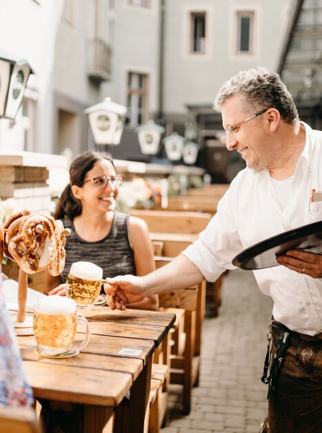 Un cameriere serve birra e brezel ai clienti nel giardino del ristorante Gösserbräu. | © glddggrs-35