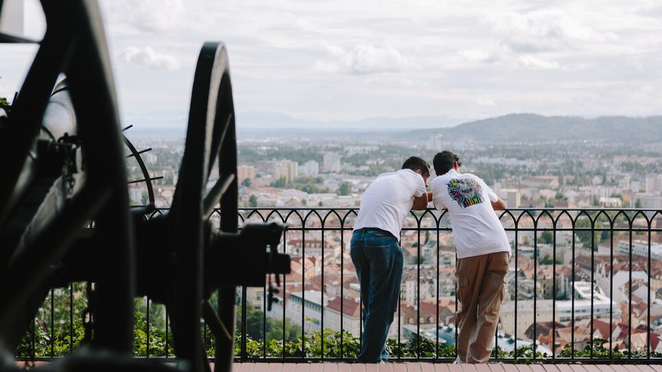 Two men lean over a railing overlooking Graz. | © Sebastian Reiser