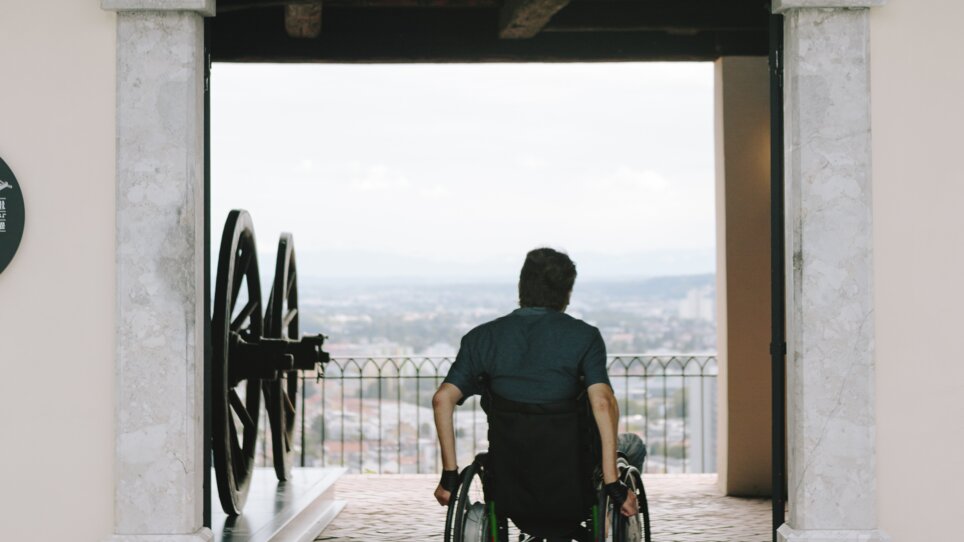A person in a wheelchair looks out at the city of Graz. | © Sebastian Reiser