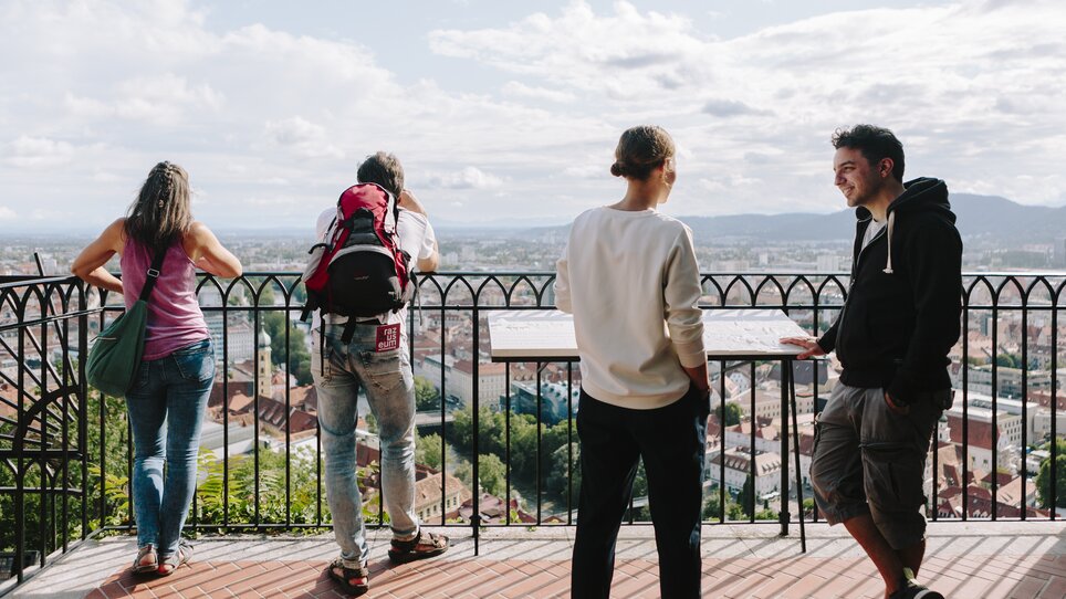 Four people enjoy the view of Graz and the clock tower. | © Sebastian Reiser
