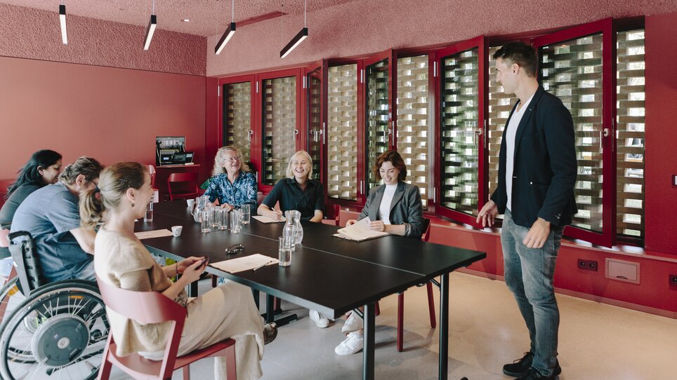 Participants engaged in a meeting in a modern space, focusing on networking. | © Sebastian Reiser