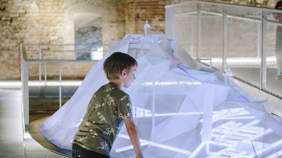 A boy looks at an interactive, glowing installation in a modern space. | © Sebastian Reiser