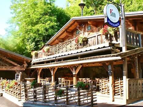Außenansicht der Almhütte Graz mit Sitzgelegenheiten und Pflanzen. | © I AM Hotels