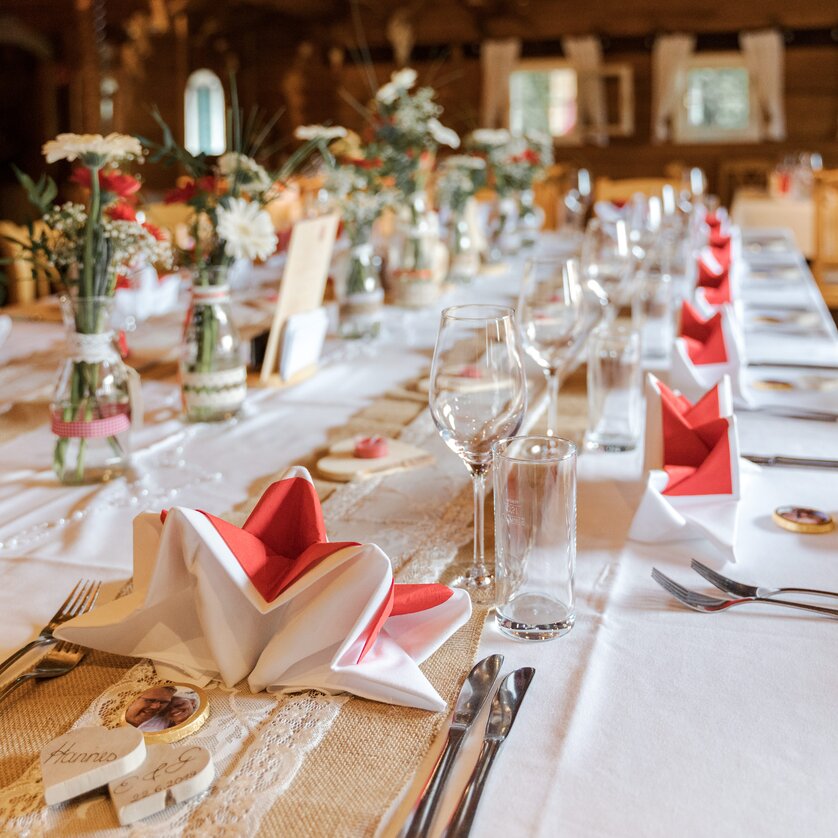 Festlich gedeckter Tisch in der Almhütte Graz mit Blumen und Servietten. | © I AM Hotels