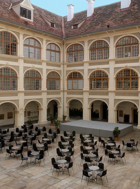 Lichtdurchfluteter Innenhof mit Stühlen, Tischen und Bühne für Veranstaltungen. | © Universalmuseum Joanneum