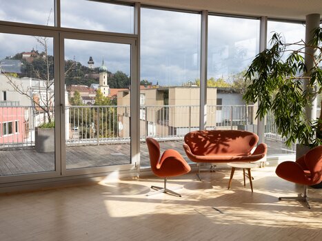 Die Level 4 Eventlocation bietet helle, moderne Räumlichkeiten mit Panoramafenstern, eleganten Möbeln und Blick auf den Grazer Uhrturm, ideal für Business-Events. | © Level 4