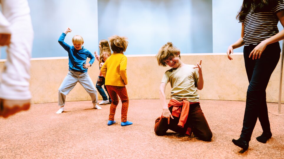 A group of children dances and plays in a bright room with high ceilings. The space offers a pleasant, inviting atmosphere. | © Stella Kager