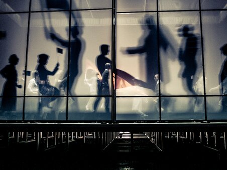 Le persone si muovono nel Next Liberty, caratterizzato da un'architettura moderna con ampie finestre e una sensazione di spazio aperto. L'illuminazione crea un'atmosfera dinamica per conferenze e networking. | © Lupi Spuma