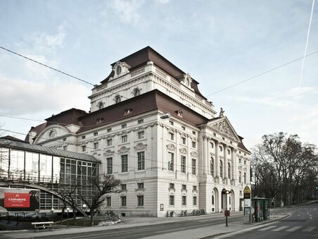 Graz Opera House with historic façade, glass bridge and bus stop on an empty street | © Moodley Brand Identity