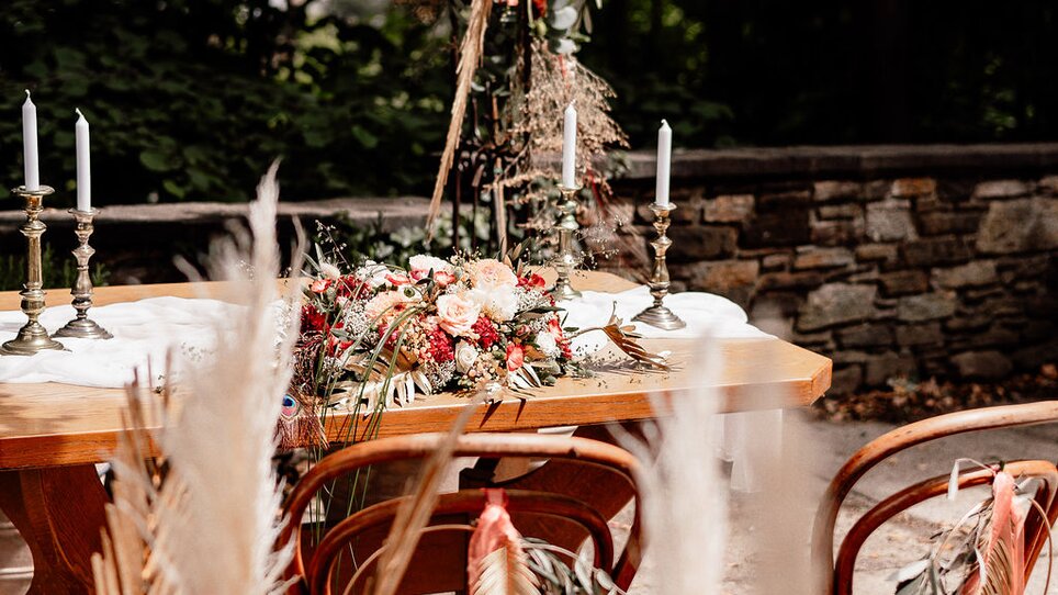 Eine stilvolle Tafel im Freien mit Blumen und Kerzen beleuchtet in einem grünen Umfeld beim Palais St. Georg. | © Palais St. Georg